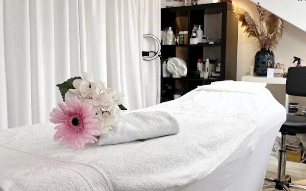 Behandelbed met een handdoek en een roze gerbera